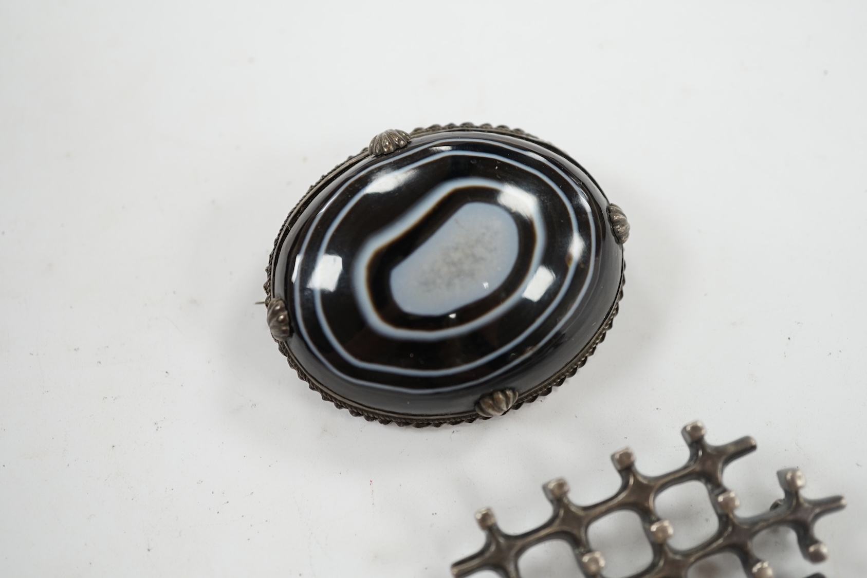 A 1960's Norwegian silver 'trellis' design brooch by David Andersen, import marks for London, 1969, 57mm, together with a white metal mounted cabochon banded agate brooch. Condition - fair